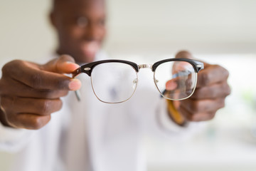 African american optiian man holding and showing glasses lens to custumers at the optics shop while...