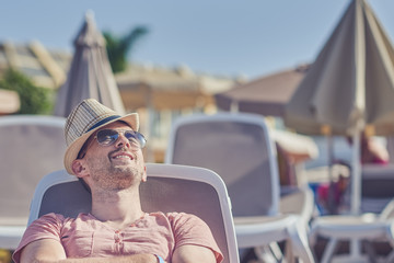 Smiling European man is relaxing in the sunbed during his vacations.