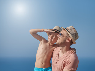 Portrait of son and dad relaxing on hotel balcony on summer holidays. Father is holding son on hands and smiling.