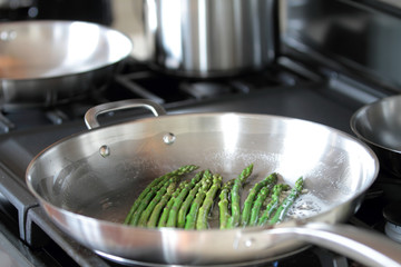 Asparagus with minced garlic and oil cooking on a pan.