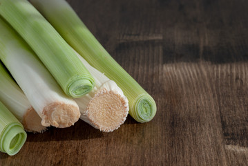 Horizontal top view of leeks on dark wood background with copy space