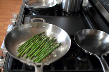 Asparagus with minced garlic and oil cooking on a pan.