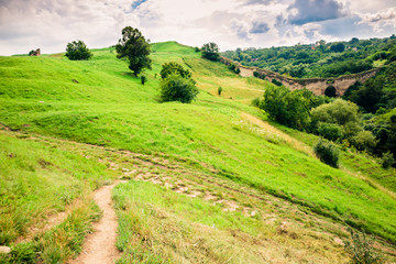 Fototapeta na wymiar Summer view of green hills and old watchtower ruins. Khotyn Fortress location. Dramatic scene of green hills landscape. Traveling concept background