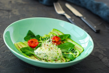 zucchini grilled with tomatoes and cream cheese, sauce and micro-greens (warm salad appetizer). food background. copy space