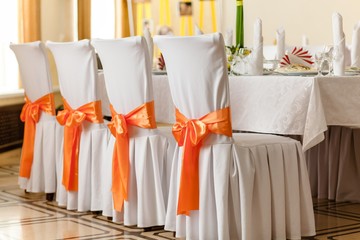 Chairs with orange bows in a wedding interior