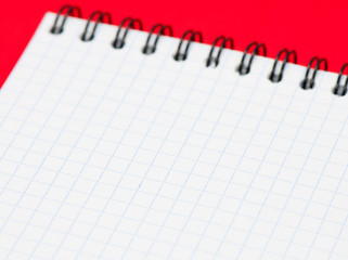 Blank sheet of a notebook (squared), on red background