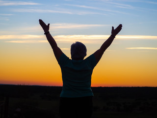 Fototapeta na wymiar A senior woman practicing yoga at sunset