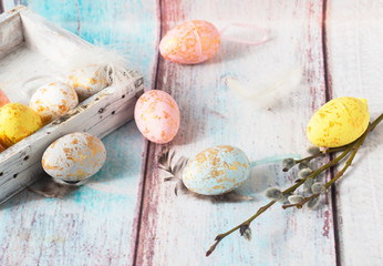 Easter eggs on a wooden background with willow and feathers