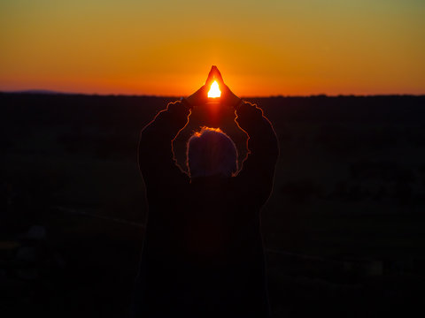 A senior woman practicing yoga at sunset