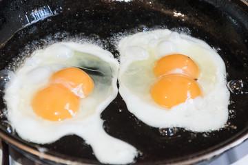 Huevos  fritos de dos yemas en una sartén 