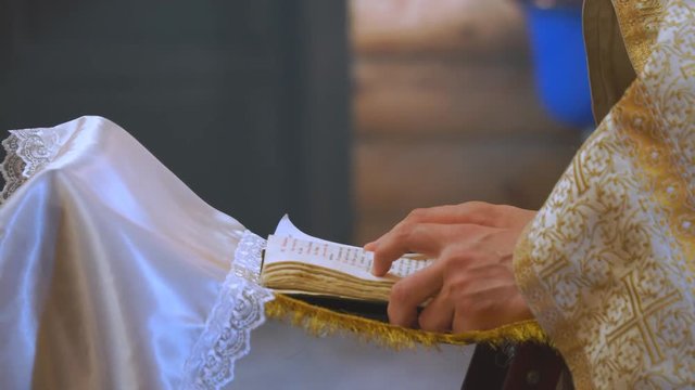 The book is in the hands of a priest or clergyman