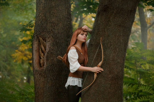 attractive elven archer not ready to shoot a victim with a wooden bow arrow, a kind and sweet girl with long red hair in leather clothes, daring and brave lady is alone in a green summer forest