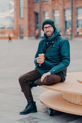 Concept of drinks and lifestyle. Carefree satisfied European man with bristle enjoys sunny day and...