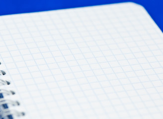 Blank sheet of a notebook (squared), on blue background