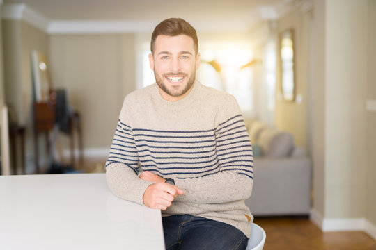 Young handsome man wearing a sweater at home with a happy and cool smile on face. Lucky person.