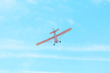 Fototapeta na wymiar Small single-engine old vintage plane flying against the blue sky