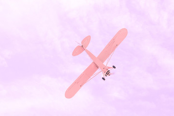 Small single-engine old vintage plane flying against the pink sky, concept of dream, happy future and positive outlook on life