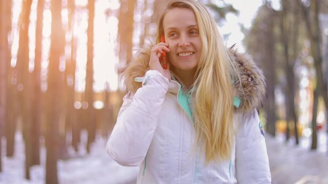 Woman is using smartphone at sunny winter day outdoors.