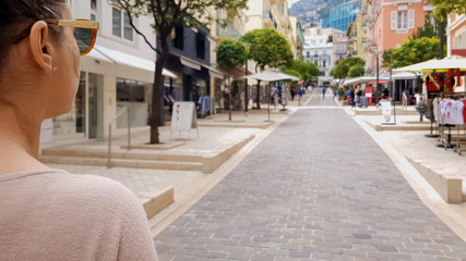 Young lady walking along street with shops, looking for sales, European city