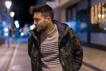 Young handsome man possing and smiling. Street style at night