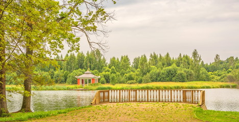 Summer landscape with gazebo on  river bank in  park