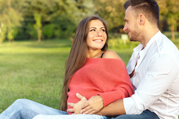 Obraz premium Her biggest support. Portrait of a young pregnant couple relaxing on the grass together looking at each other with love