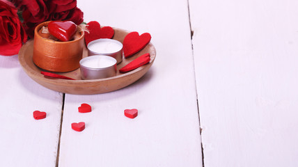 Valentine's Day with candles, red roses, white table and red hearts
