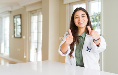 Young woman wearing medical coat at the clinic as therapist or doctor approving doing positive...