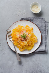 Fettuccine pasta with traditional Italian Passat sauce and parmesan cheese in light plate on old white concrete background. Top view.