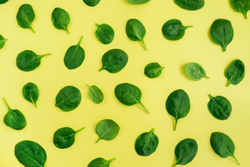Green fresh vegetarian salad leaves on yellow background. Top view.