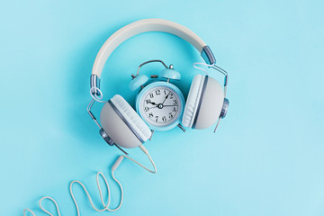 Retro headphones and alarm clock on blue background