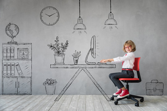 Happy child sitting at the desk in imaginary office