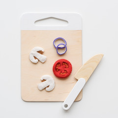 Waldorf toys background. Wooden knife and cutting board with felt foods: mushrooms, tomato and onion