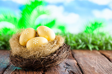 Three painted Easter eggs in the nest on table and nature background