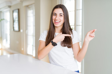 Fototapeta na wymiar Beautiful young woman wearing casual white t-shirt smiling and looking at the camera pointing with two hands and fingers to the side.