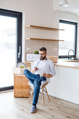 A mature man with smartphone moving in new home, text messaging.