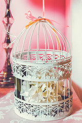 Candy Bar. The cage with flowers stand in restaurant . white roses put on the top of bird cage