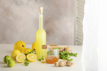 Bottle of homemade juice with ginger and lemon on light background. Horizontal