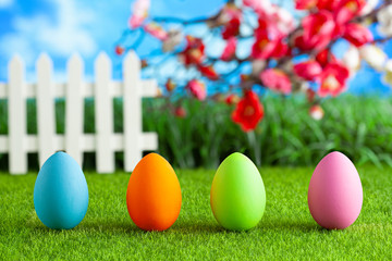 Four colored eggs on grass and spring nature background
