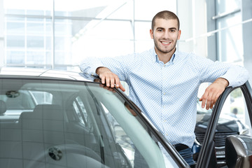 His dream car. Young handsome man standing near the car he is buying smiling happily