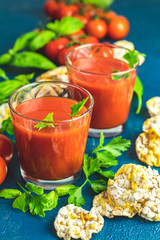 Red cocktail with tomato juice between tomatoes, basil, parsley and nutritious cereal breads