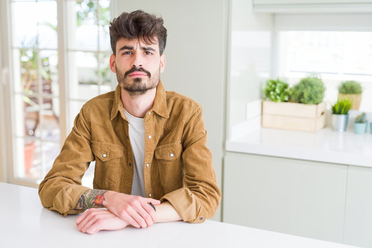 Young man wearing casual jacket sitting on white table depressed and worry for distress, crying angry and afraid. Sad expression.