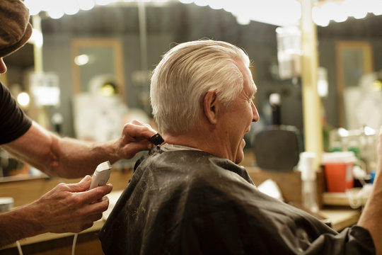 Senior man laughs while getting his hair cut