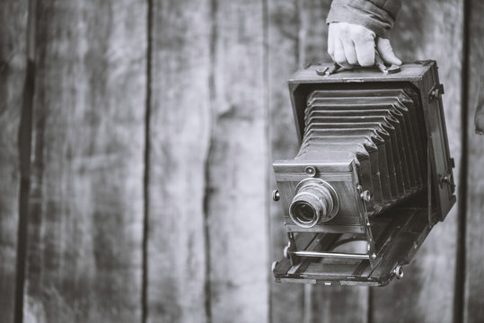 Large format retro camera, 5x7 inches. Photographer holds old studio camera. Monochrome effect, copy space. Concept - photography of the 1930s-1950s