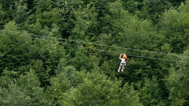 Woman moving on zip line. Woman moves on zip line above the canyon