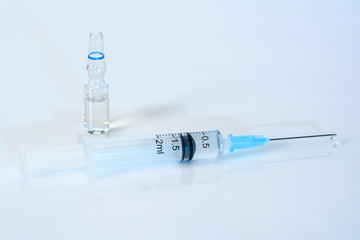 Syringe on a light blue background with medicinal solution. 2 ml syringe close up, with an ampoule of medicine