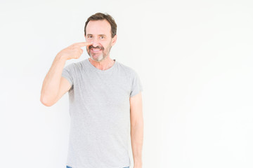 Obraz premium Handsome senior man over isolated background Pointing with hand finger to face and nose, smiling cheerful