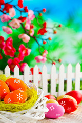 Painted Easter eggs in the nest and wooden table and branches with colorful spring flowers