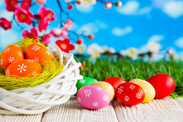 Easter eggs in the nest and wooden table on nature background