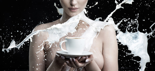 Milk splashing against a nude woman holding a cup of coffee